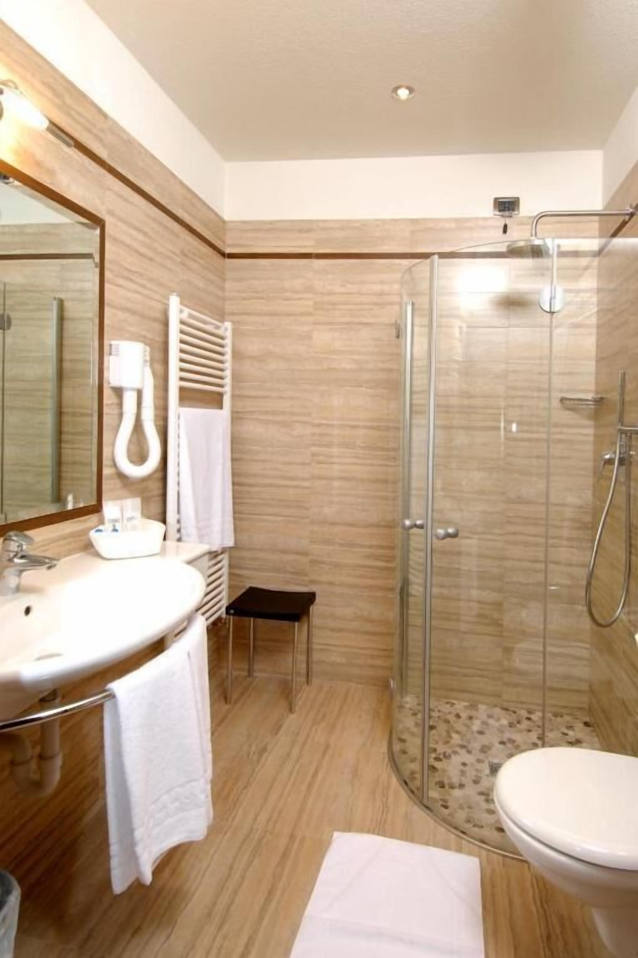 A modern bathroom with a glass-enclosed shower, a sink with a mirror, and a toilet.
