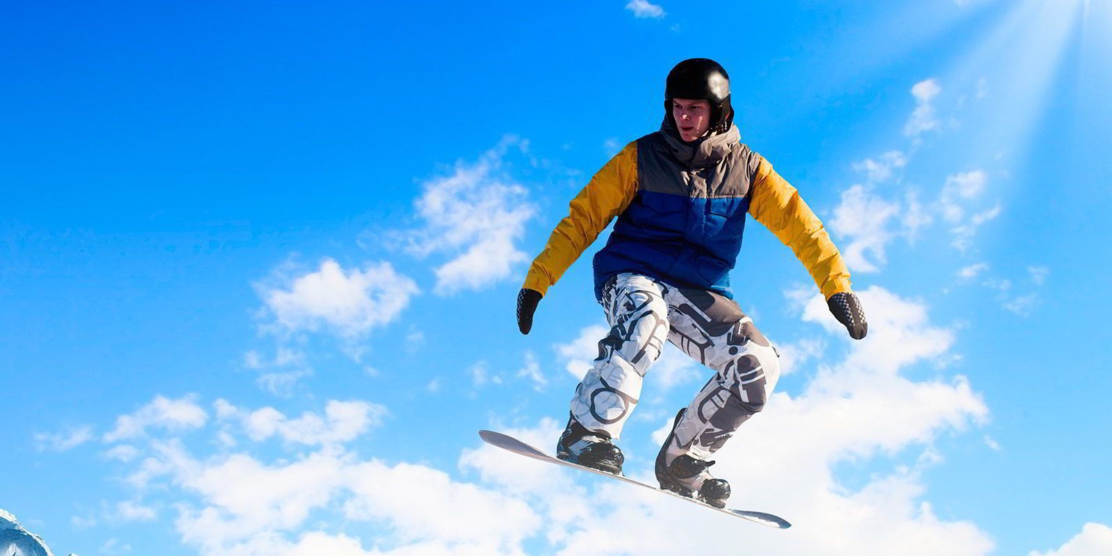 Uma pessoa praticando snowboard contra um céu azul límpido.