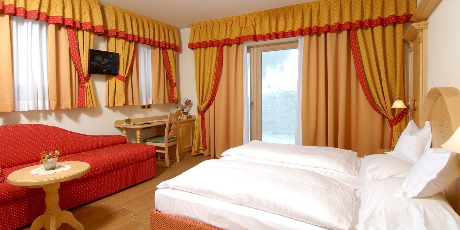 A hotel room with a bed, a desk, a chair, and a sofa.