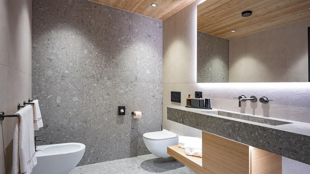 A modern bathroom with a large mirror, a toilet, and a sink.