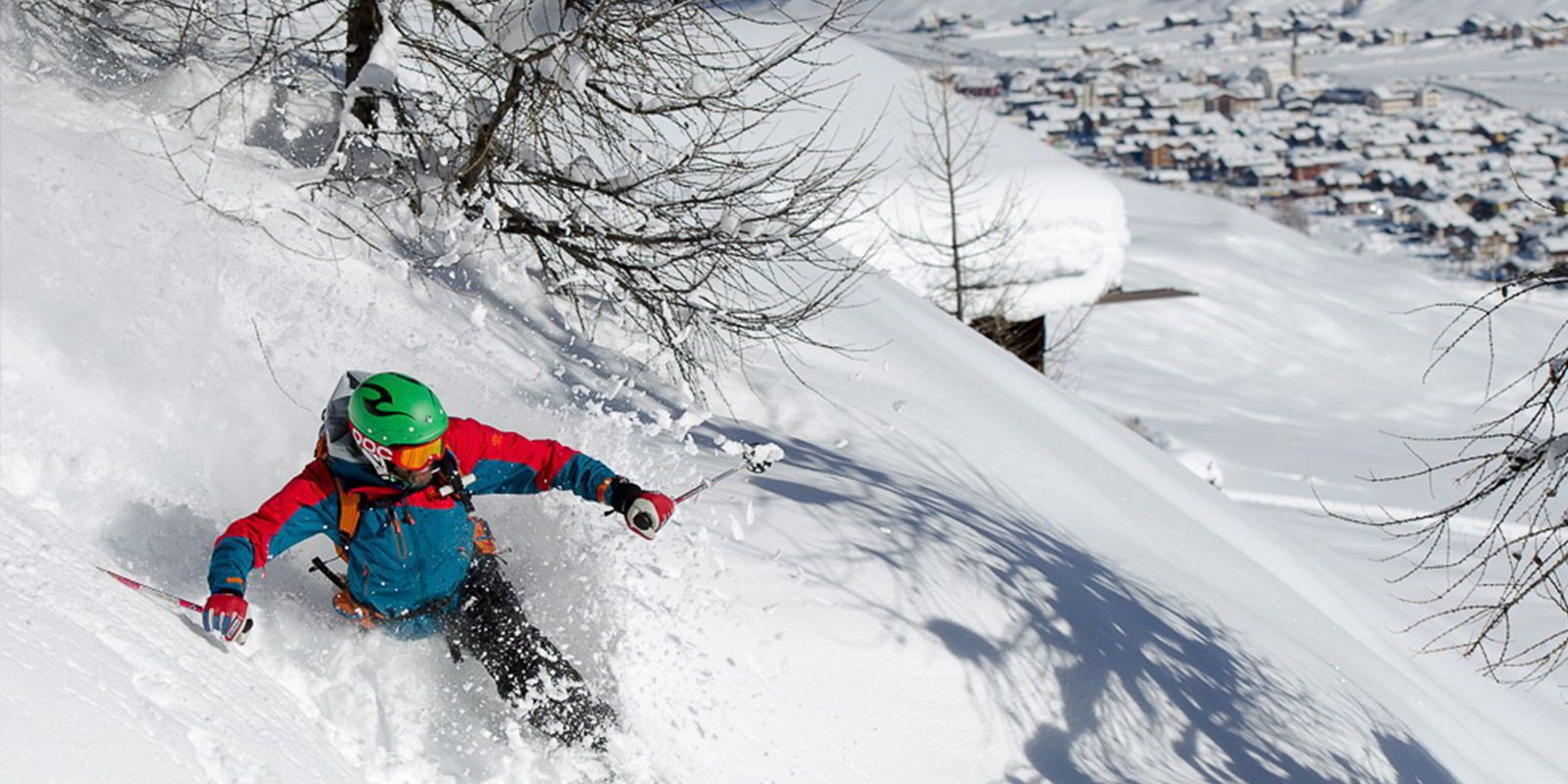 A skier on a snowy slope with a town in the background.