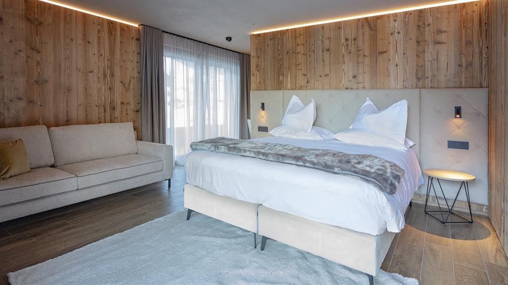 A modern bedroom with a large bed, a sofa, and a small table.