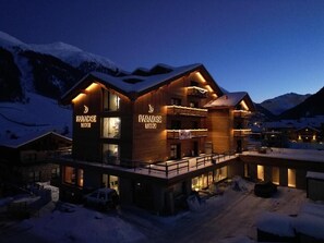 A two-story wooden building with illuminated signs reading "Paradise Lodge" and "Paradise Lodge."