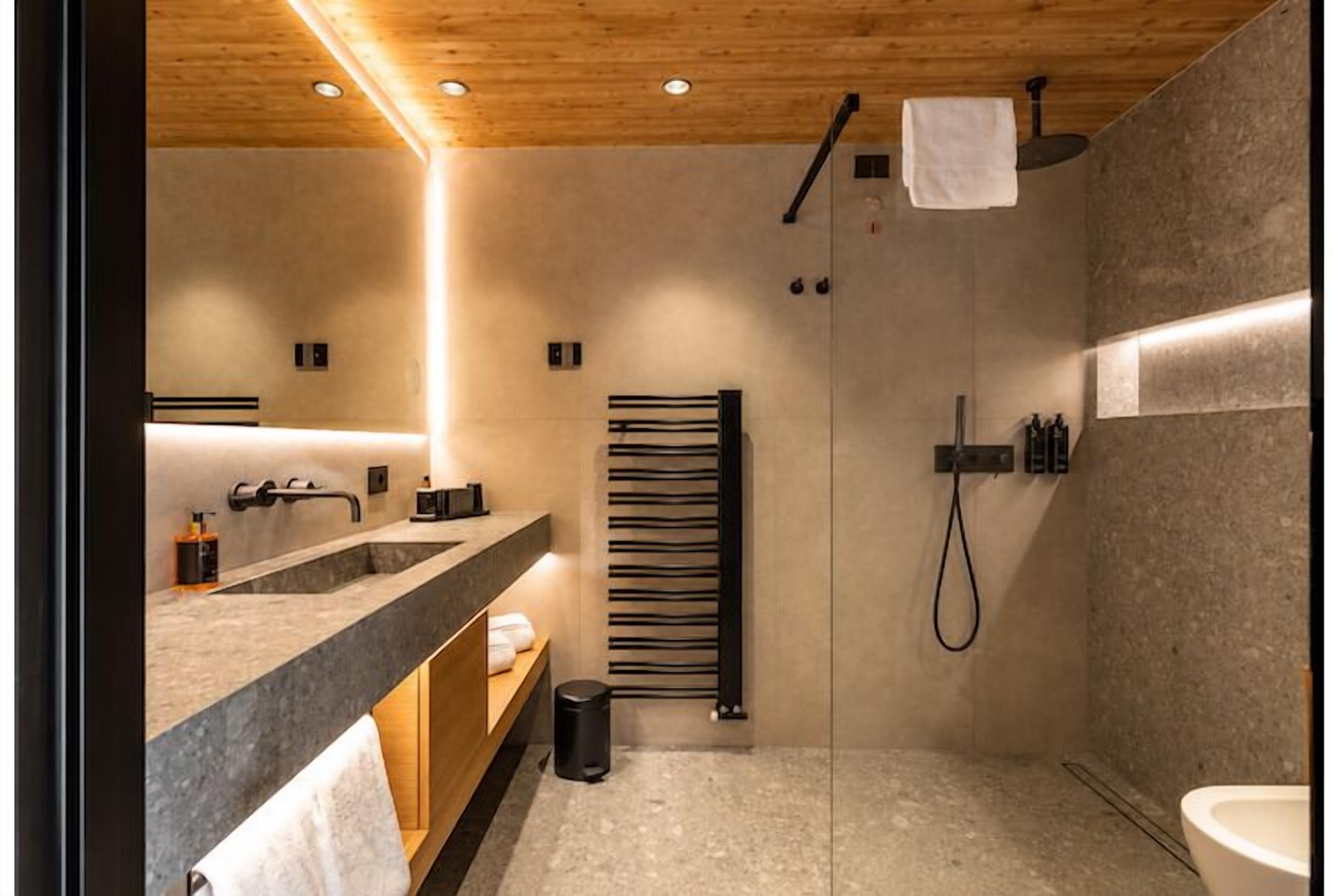 A modern bathroom with a wooden ceiling, a large mirror, a shower, and a sink.