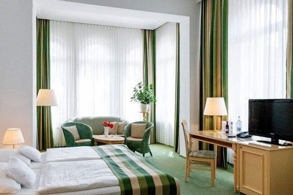 Ein Hotelzimmer mit Bett, Schreibtisch, Stuhl, Fernseher und Pflanze.