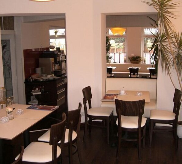 Un espace repas avec une table et des chaises, un coin cuisine avec des placards et des appareils électroménagers, et une vue sur un espace extérieur aménagé avec des tables et des chaises.