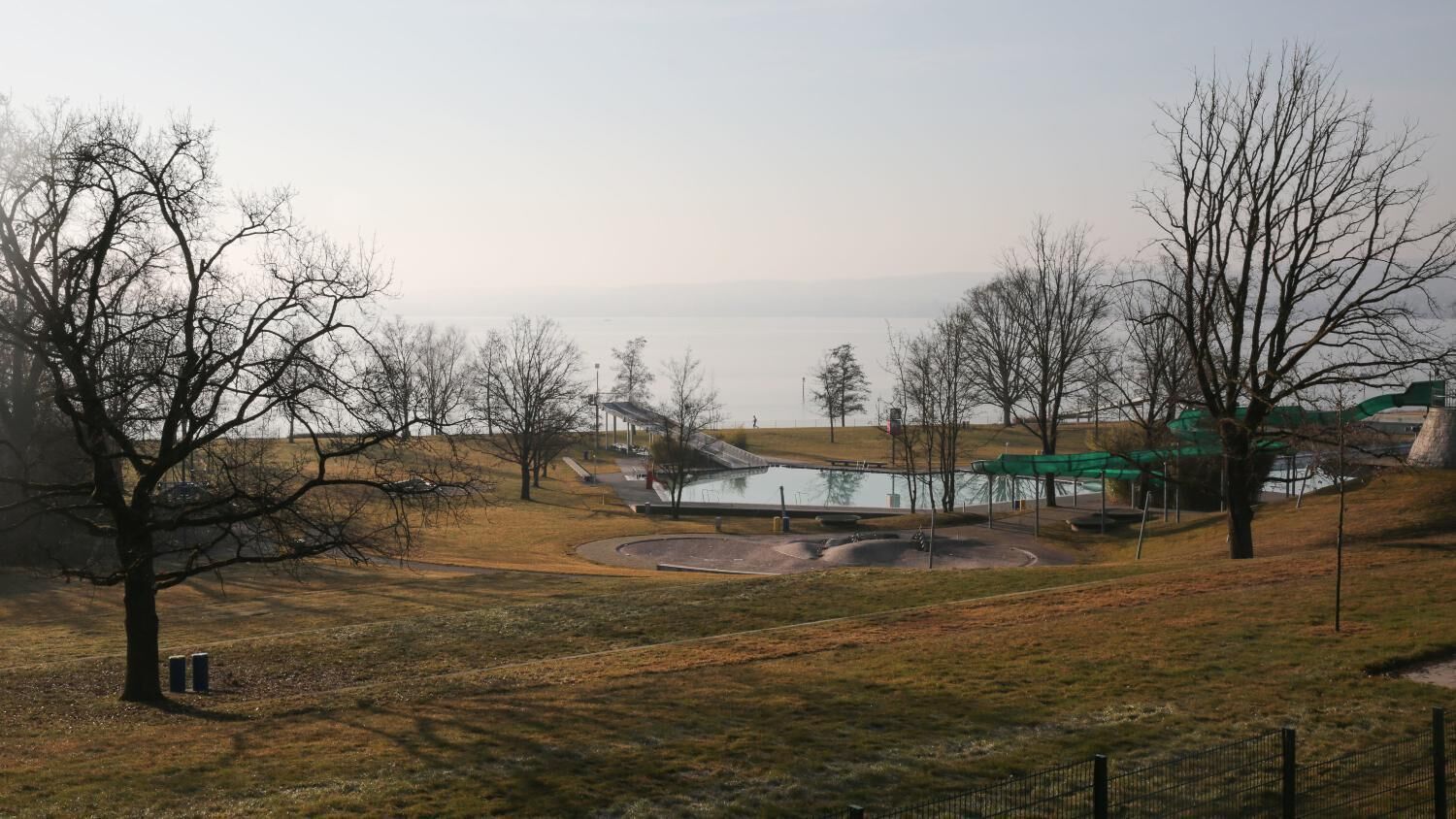 Ein Park mit Teich, Wegen und Bäumen.