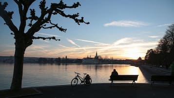 Un banc et un vélo au bord d’une rivière paisible, avec un coucher de soleil en arrière-plan.