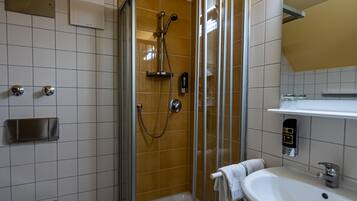Un baño moderno con ducha de vidrio, lavamanos blanco y un inodoro.