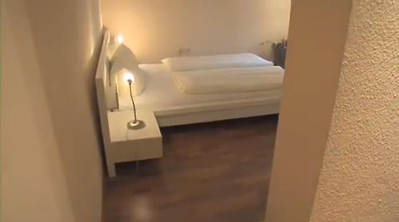 A bedroom with a bed, a nightstand, and a lamp.