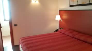 Een hotelkamer met een bed, nachtkastje, lamp en een schilderij aan de muur.