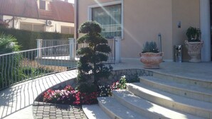 A building with a stone staircase leading to a door, surrounded by a metal railing and potted plants. - Hotel Gullo (Curinga)
