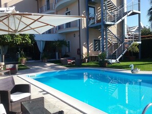Una piscina al aire libre, sombrillas, tumbonas