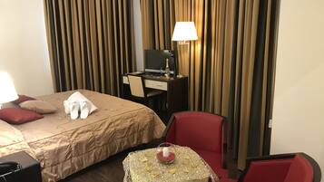 Une chambre d’hôtel équipée d’un lit, d’un bureau, d’un ordinateur, d’une chaise et d’une petite table agrémentée d’un élément décoratif.