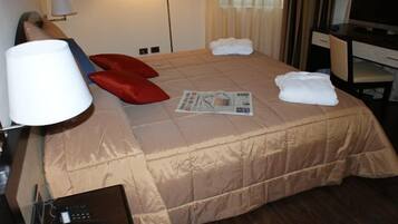 Una habitación de hotel con cama, escritorio, computadora, lámpara y teléfono.