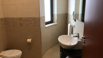 Ein Badezimmer mit Toilette, Waschbecken und Fenster.