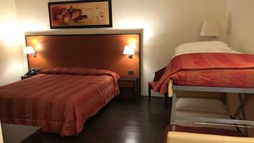 Ein Hotelzimmer mit zwei Betten, einem Nachttisch mit Lampe, einem Bild an der Wand und einem Holzkopfstück.