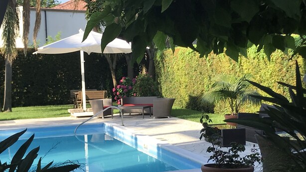 A swimming pool with a stone deck, surrounded by potted plants and a bench. - Hotel Gullo (Curinga)