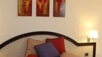 Ein Hotelzimmer mit einem Bett, Kissen, einem Nachttisch mit Lampe und drei an der Wand hängenden Bildern.