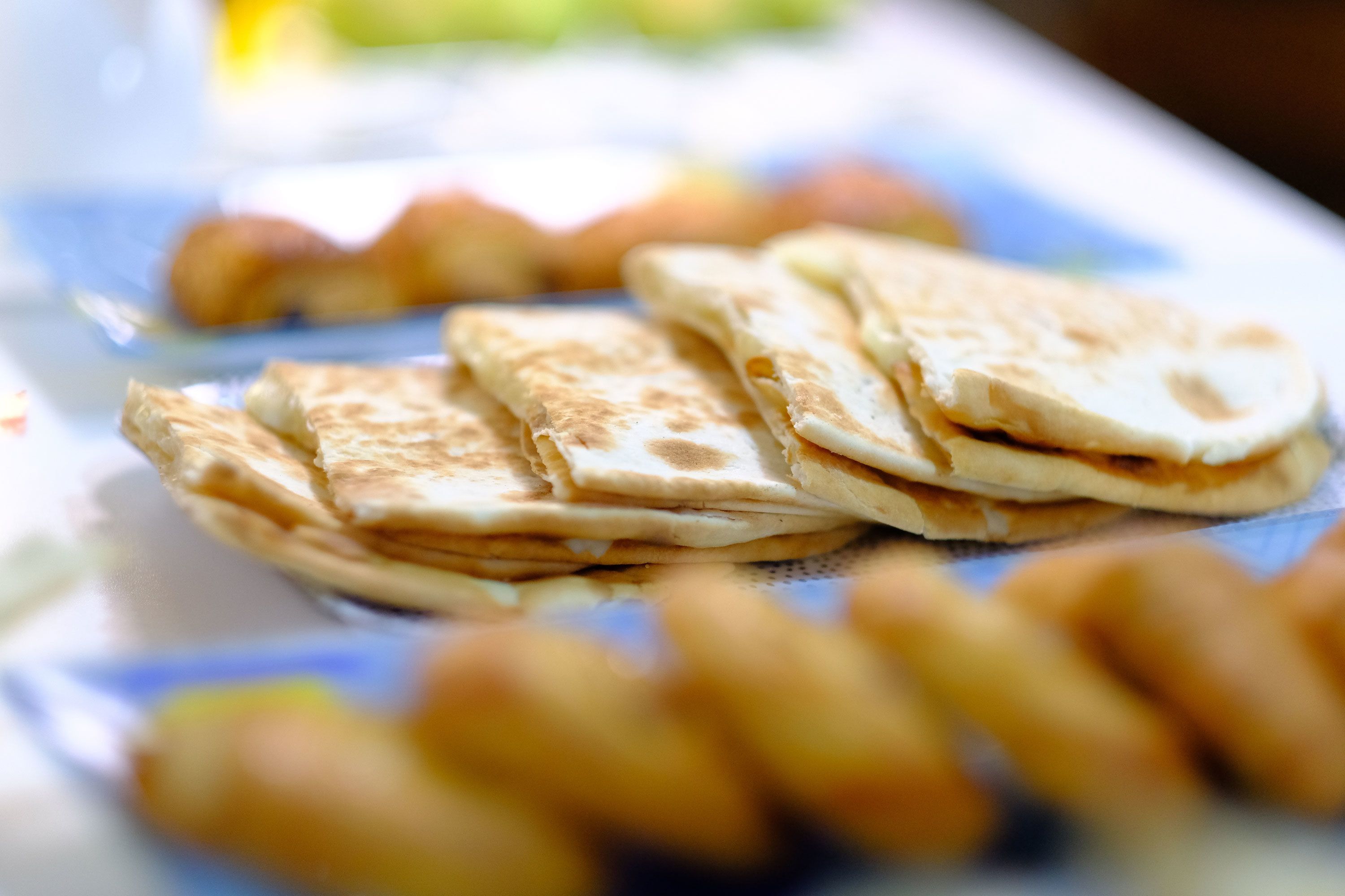 A plate with several pieces of flatbread and some other food items.