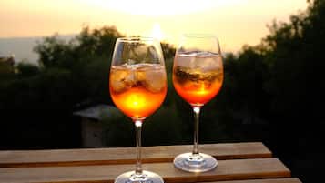 Twee glazen van een drankje op een houten ondergrond, met een zonsondergang op de achtergrond.