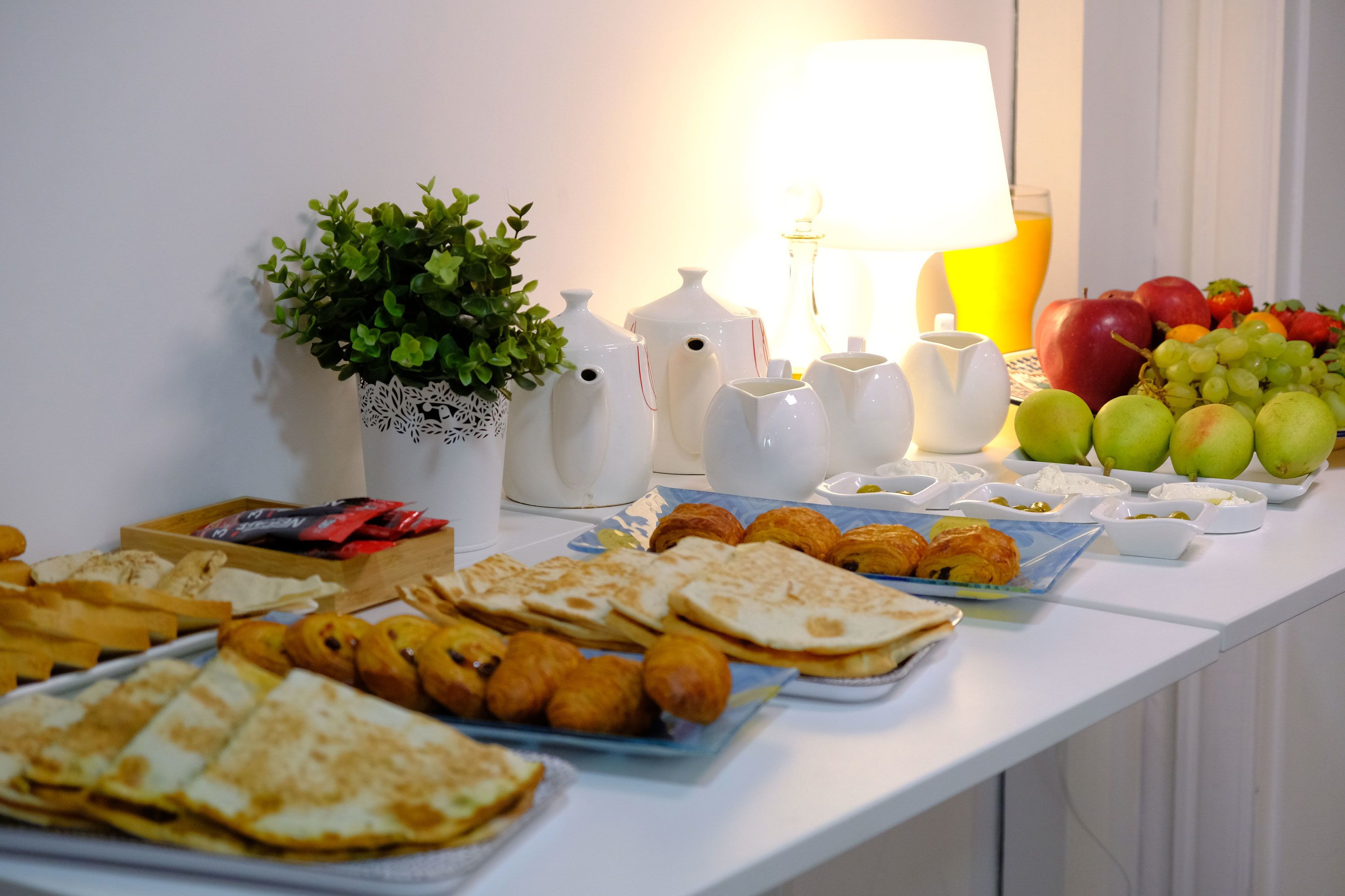 A breakfast buffet with various pastries, fruits, and beverages.