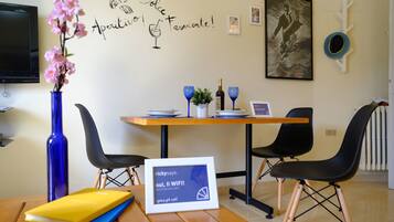 A dining area with a table, chairs, a vase with flowers, a framed picture, and a sign with a computer screen.