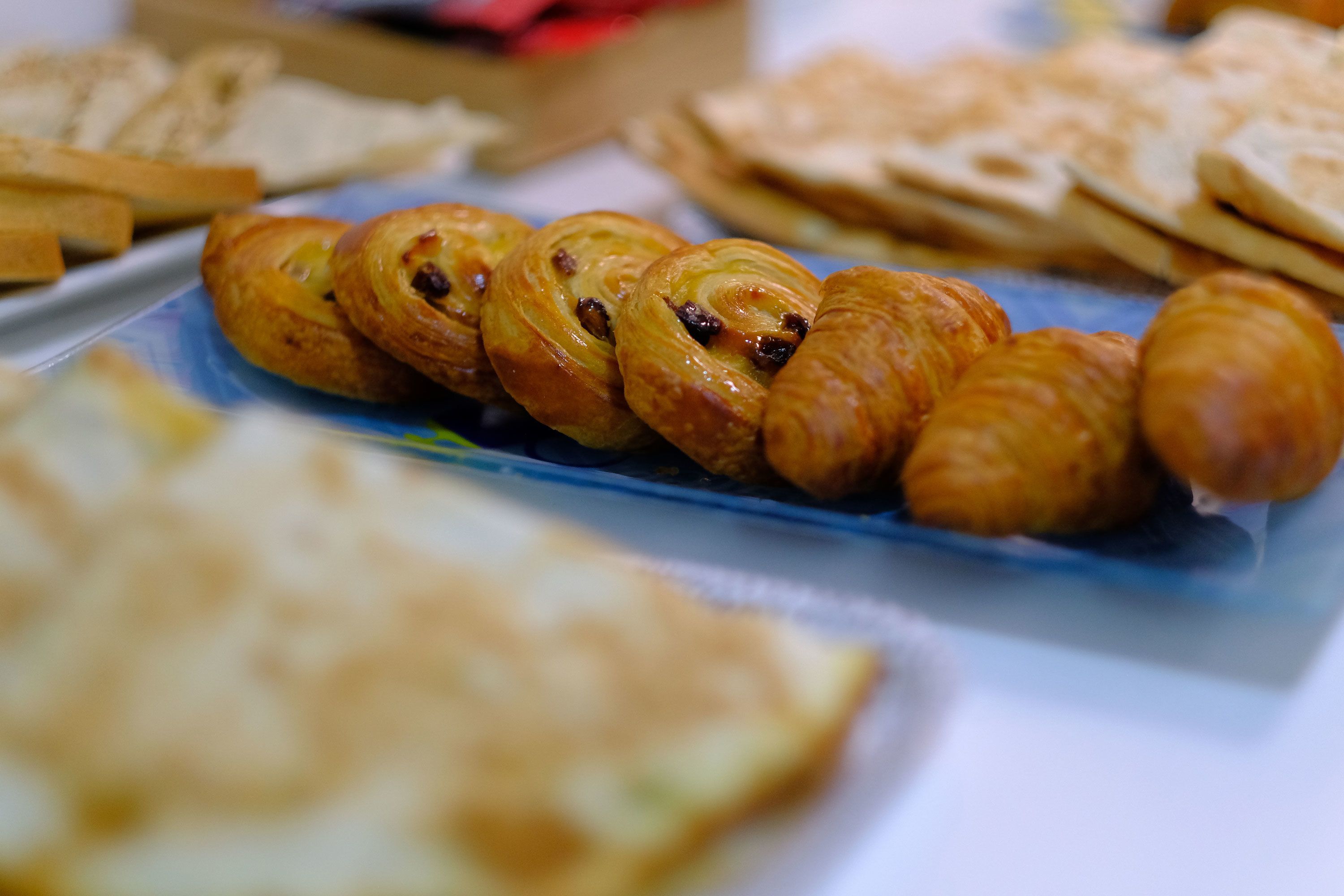 Et udvalg af kager og bagværk på et fad, blandt andet croissanter.