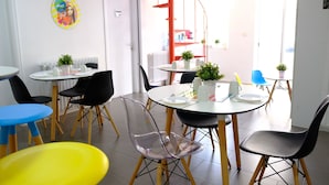 Un comedor moderno con mesas redondas, sillas negras y amarillas, y plantas en macetas.