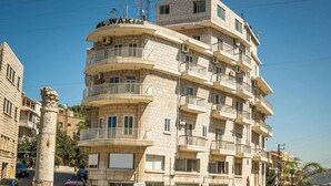Un edificio de varios pisos con balcones, una columna central y un letrero que dice "WAKI".