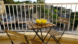 Un balcón con una mesa y sillas de madera, un plato de limones y vistas de la ciudad.