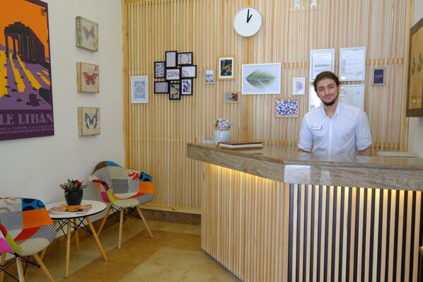 A reception area with a wooden panel wall, a clock, framed artwork, and a desk with a vase of flowers.