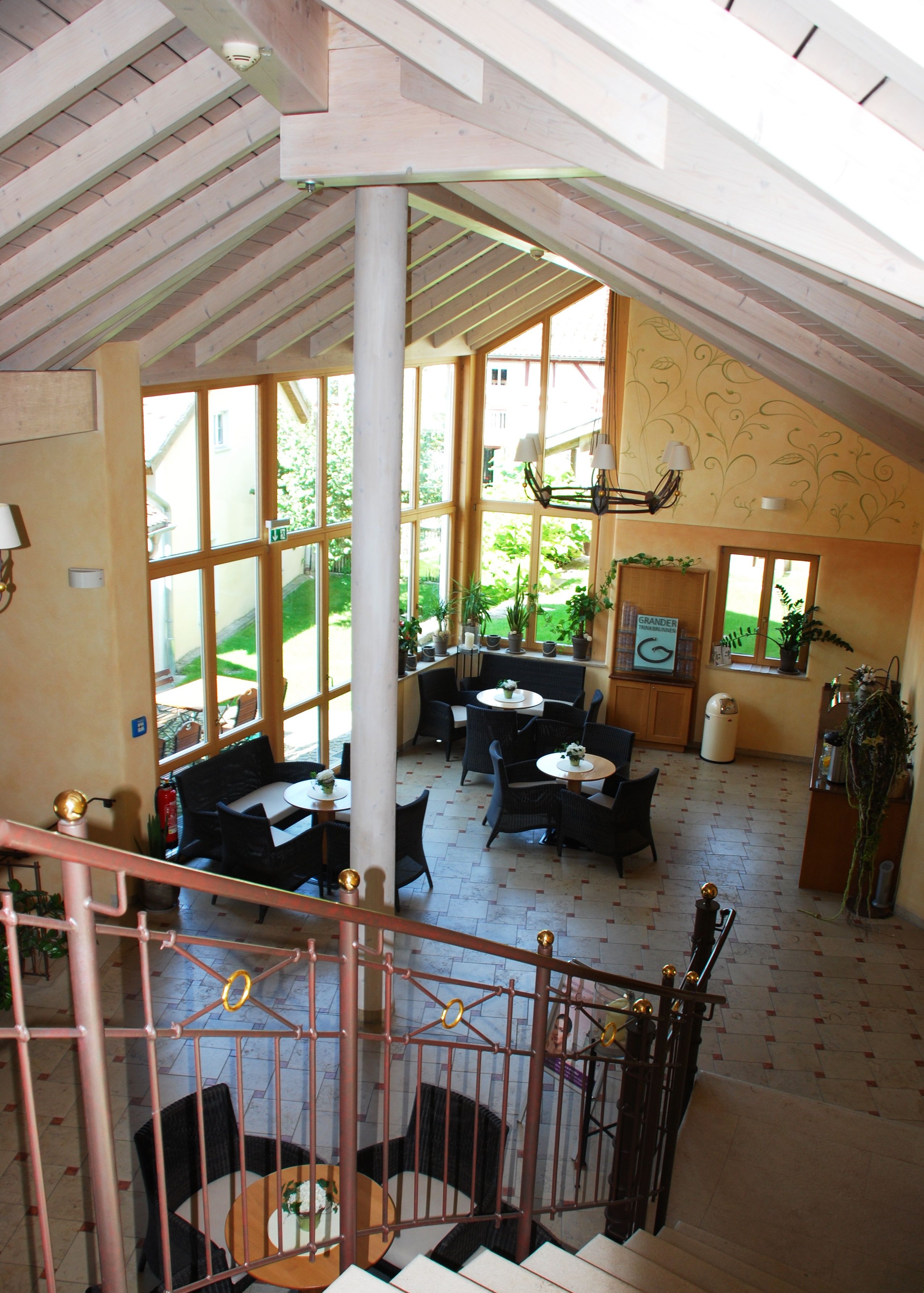 A spacious interior with a high ceiling, large windows, and a staircase leading to an upper level.