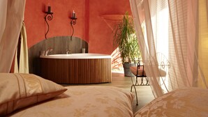 Un dormitorio con una cama grande, una bañera redonda, una planta en maceta y una silla.