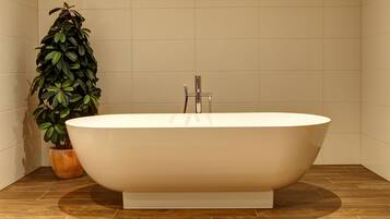 A freestanding bathtub in a bathroom with a tiled floor and a potted plant.