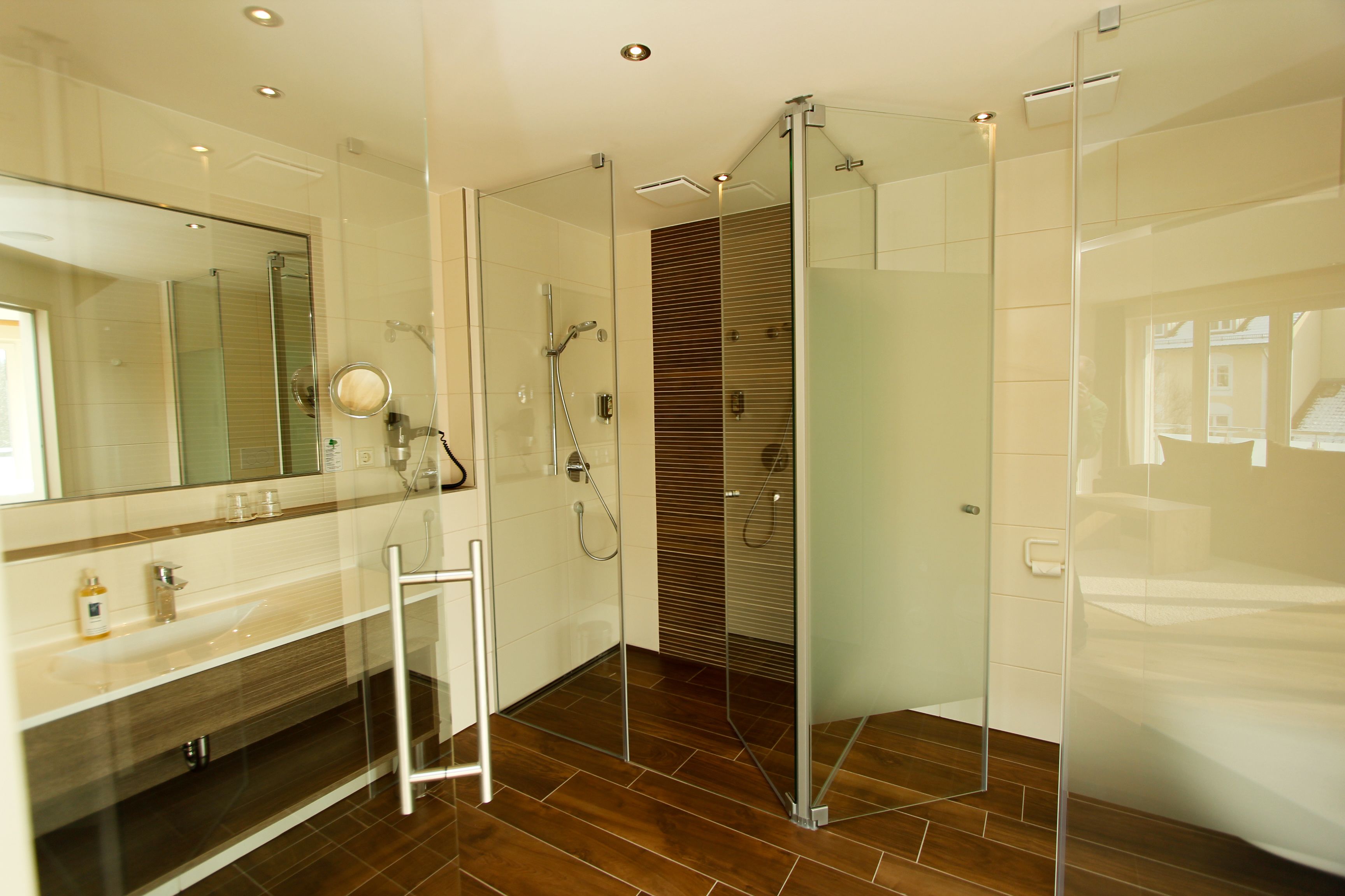 A modern bathroom with a glass shower enclosure, a vanity with a mirror, and a wooden panel wall.