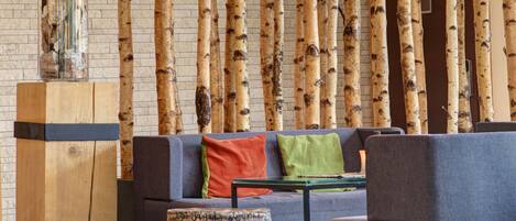 Una sala de estar moderna con sofá, reposapiés y una pared decorada con listones de madera verticales.