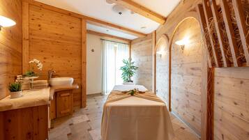 A wooden interior with a massage table, a sink, and a plant.