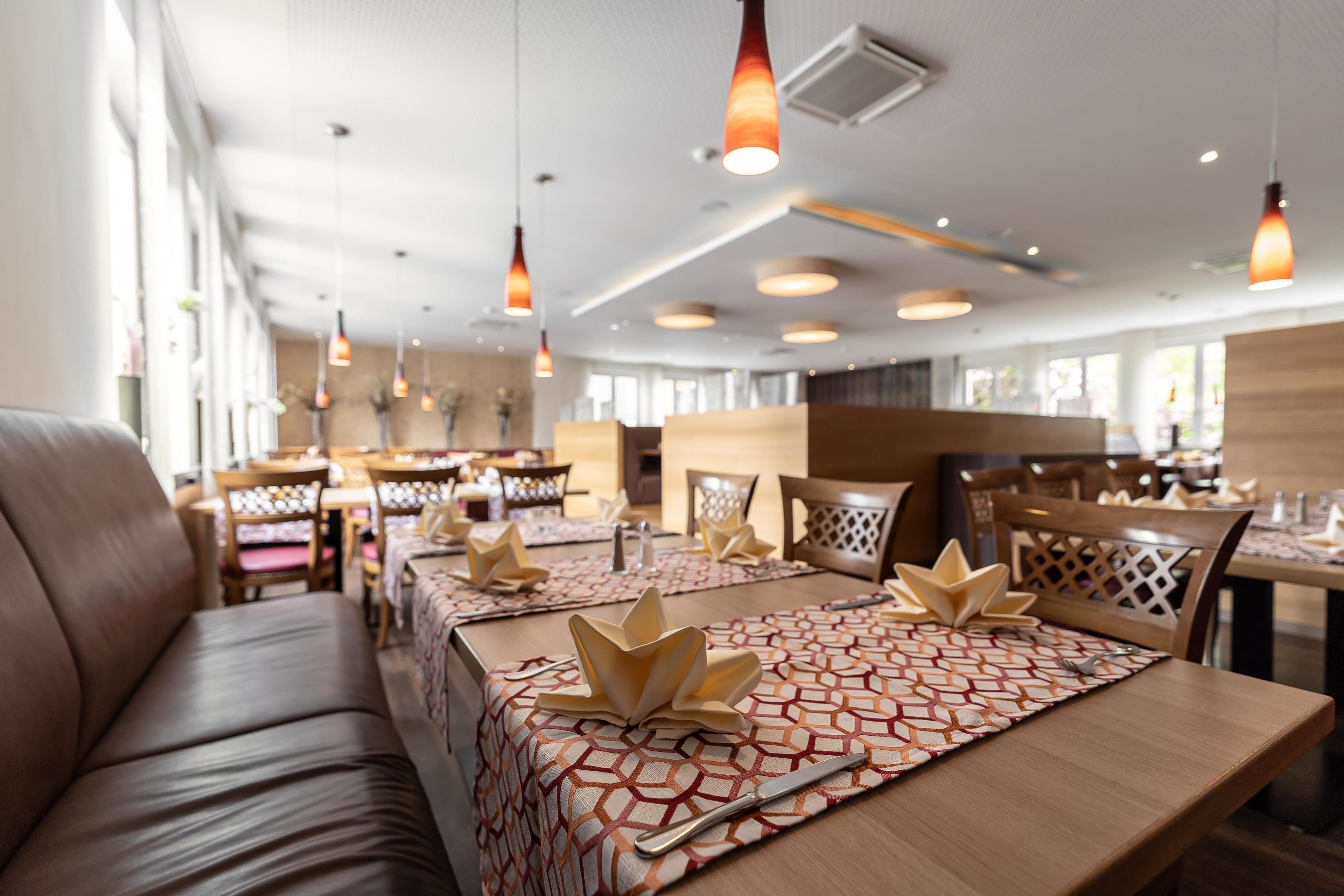 Ein Restaurant mit Holztischen und -bänken, Pendelleuchten und modernem Interieur.