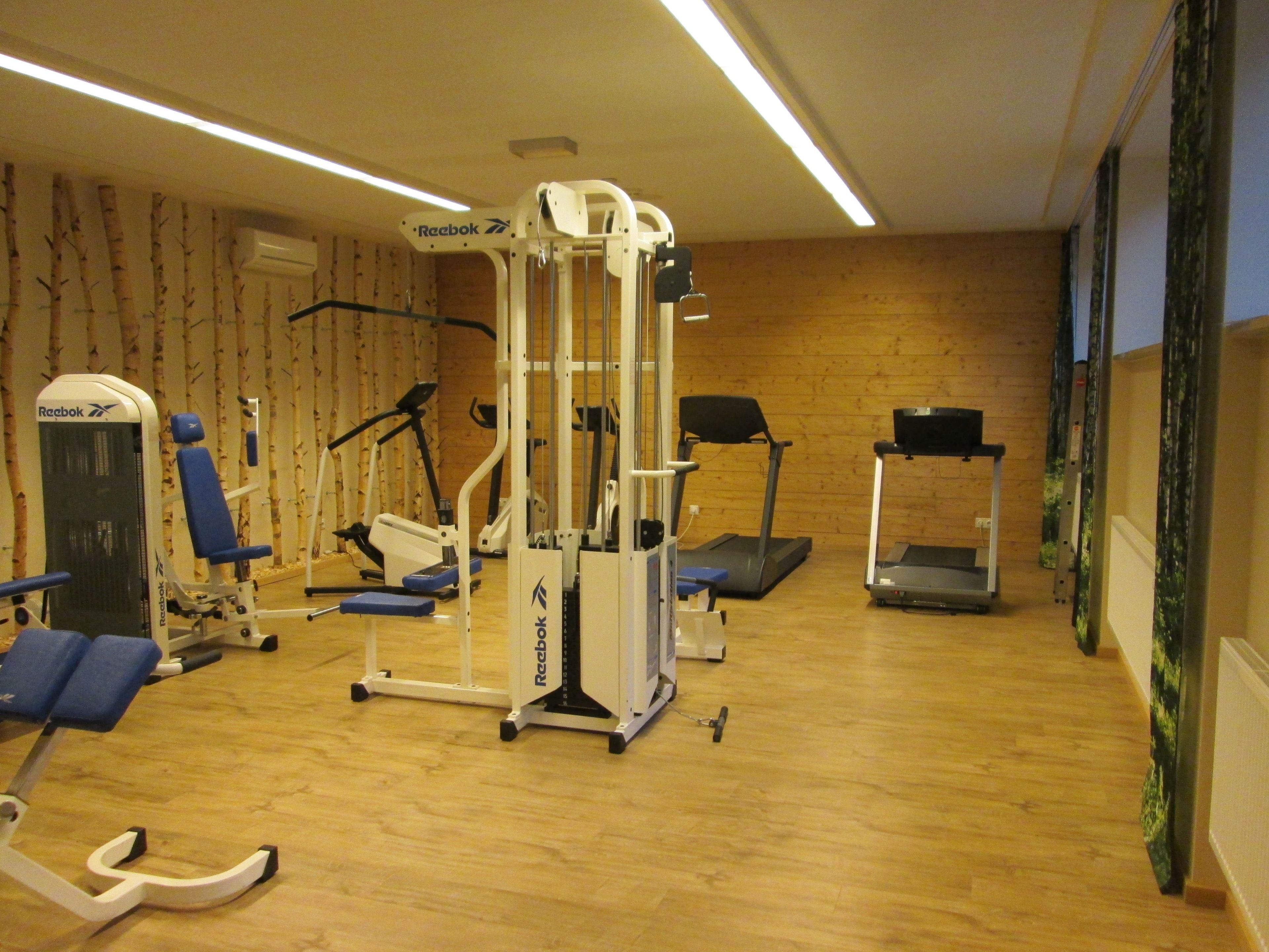 Une salle de sport équipée de divers appareils d’exercice, notamment des tapis de course et des appareils de musculation.
