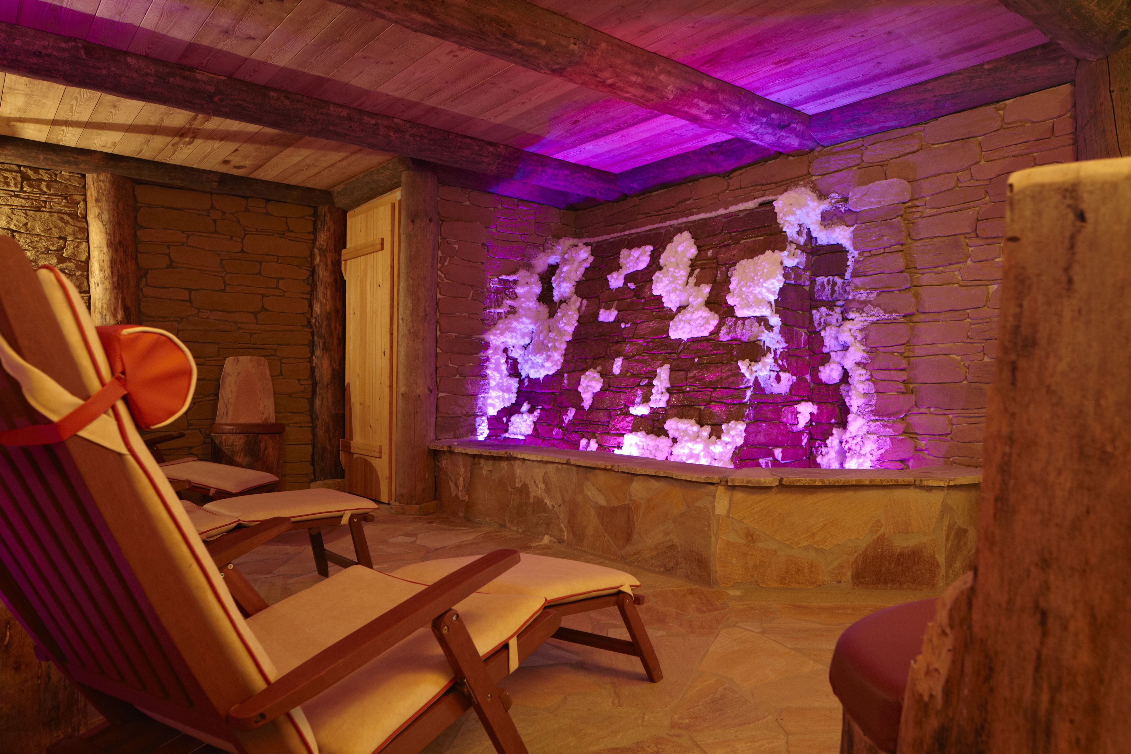 A spa room with wooden beams, stone walls, and a massage table.
