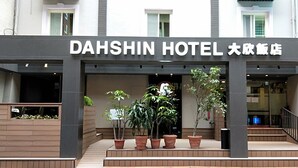 Exterior del hotel Dahshin, con un letrero, plantas en macetas y una escalera que lleva a la entrada.