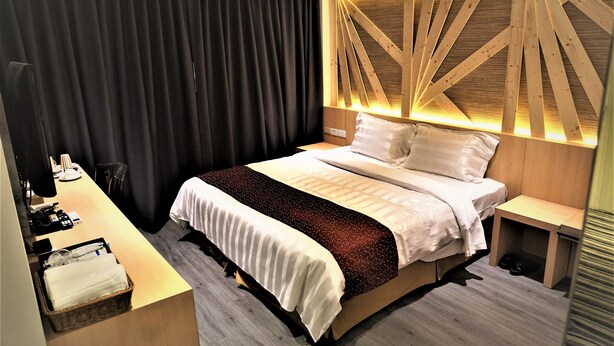 Una habitación de hotel moderna con una cama bien tendida, un escritorio con una silla y una mesita.