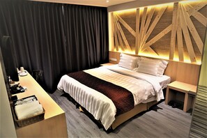 Una habitación de hotel moderna con una cama bien tendida, un escritorio con una silla y una mesita.