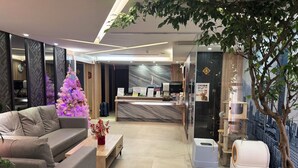 Un moderno vestíbulo de hotel con un mostrador de recepción, un árbol de Navidad, un sofá y una planta en maceta.