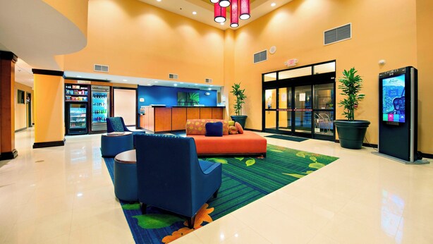 A lobby with a reception desk, seating area, vending machine, and a large potted plant. - Fairfield Inn & Suites by Marriott Charleston Airport/Convention Center (North Charleston)