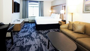A hotel room with a bed, a desk, a sofa, a coffee table, a TV, and a window with curtains. - Fairfield Inn & Suites by Marriott Charleston Airport/Convention Center (North Charleston)