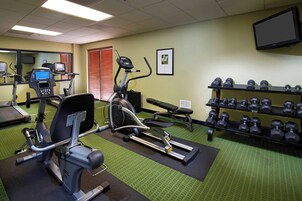 Un gimnasio con equipo de ejercicio, una televisión y un televisor montado en la pared.