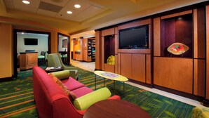 A hotel lobby with a seating area, a television, and a reception desk. - Fairfield Inn & Suites by Marriott Charleston Airport/Convention Center (North Charleston)