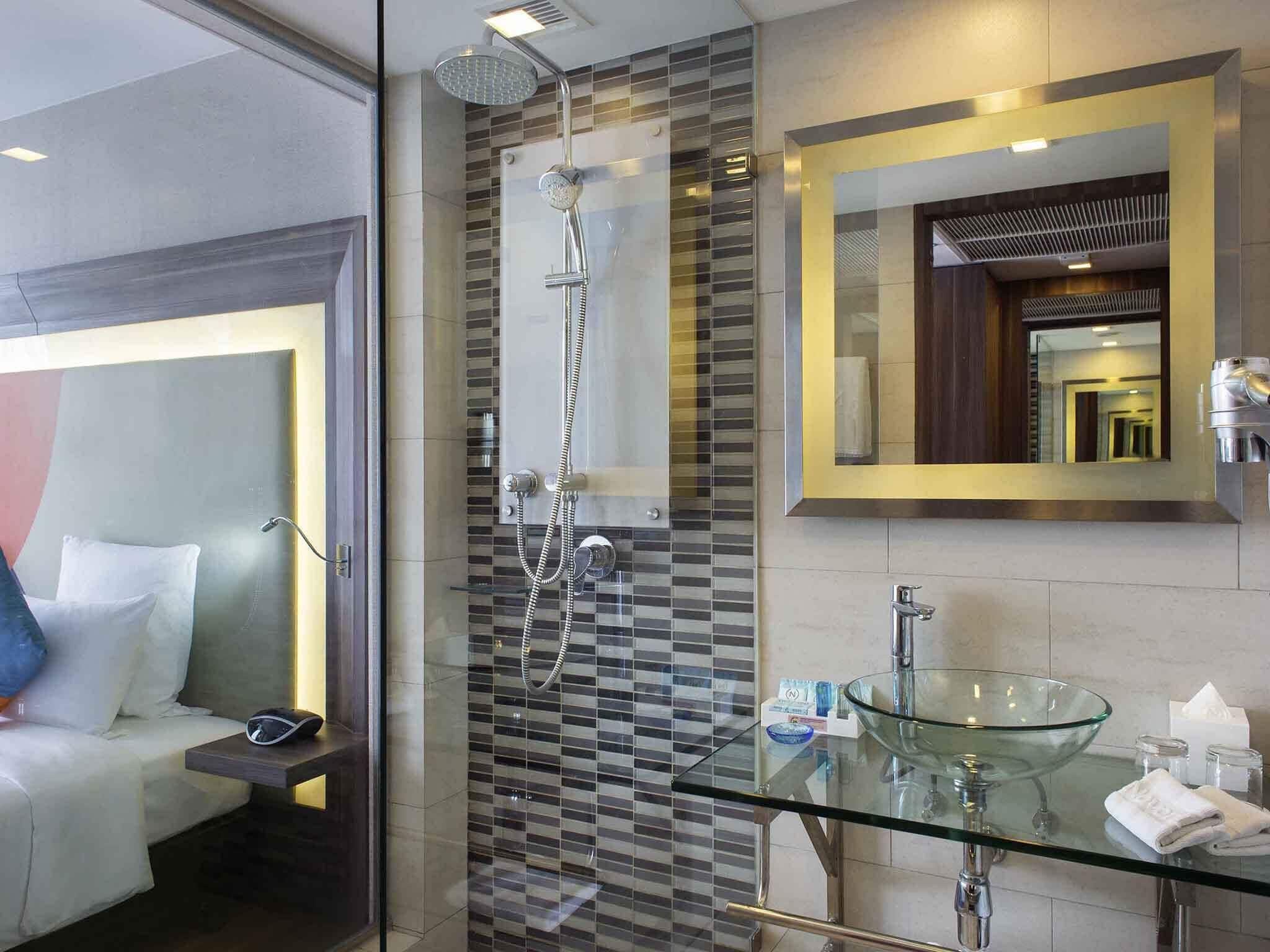 A modern bathroom with a glass-enclosed shower, a glass sink, and a large mirror.